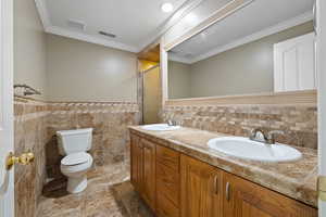 Bathroom featuring tile walls, vanity, an enclosed shower, ornamental molding, and toilet