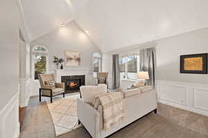 Carpeted living room with ornamental molding, a fireplace, and high vaulted ceiling