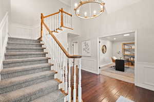 Staircase featuring a high ceiling, wood-type flooring, crown molding, and a chandelier