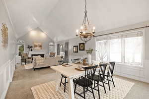 Dining area featuring crown molding, lofted ceiling, light colored carpet, and an inviting chandelier