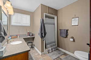 Bathroom with vanity, a shower with curtain, toilet, and a textured ceiling