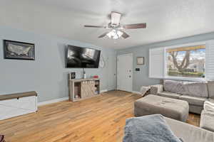 Living room featuring ceiling fan, hardwood / wood-style floors, and a textured ceiling