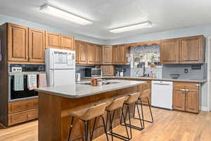 Kitchen featuring sink, a breakfast bar area, a center island, light hardwood / wood-style floors, and black appliances