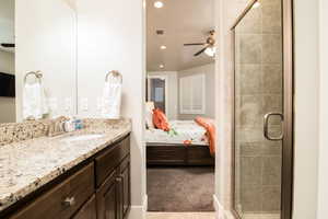 Bathroom featuring ceiling fan, vanity, and a shower with door