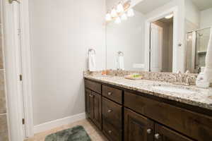 Bathroom with tile patterned flooring, walk in shower, and vanity