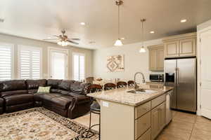 Kitchen with sink, a kitchen island with sink, appliances with stainless steel finishes, a kitchen breakfast bar, and cream cabinets