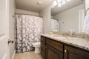 Bathroom with toilet, vanity, and tile patterned floors