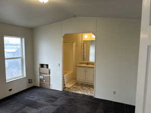 Unfurnished bedroom with light carpet, sink, and ensuite bath