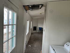 Corridor featuring washer / clothes dryer and dark colored carpet