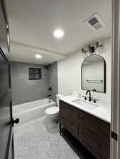 Full bathroom with tiled shower / bath combo, vanity, a textured ceiling, tile patterned floors, and toilet