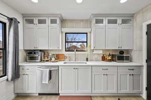 Kitchen with sink, light hardwood / wood-style flooring, white cabinetry, backsplash, and stainless steel appliances