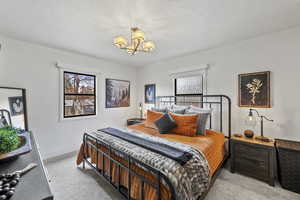 Carpeted bedroom featuring a notable chandelier and a textured ceiling