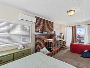 Bedroom with crown molding, carpet, a wall mounted air conditioner, and a brick fireplace