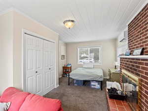 Carpeted bedroom featuring crown molding, a wall mounted air conditioner, a fireplace, and a closet