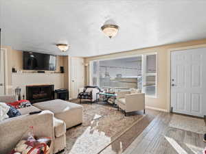 Living room with a textured ceiling, a brick fireplace, and light wood-type flooring