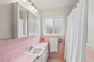 Bathroom featuring tile patterned flooring, vanity, and tile walls