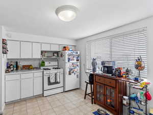 Kitchen featuring backsplash, white appliances, and white cabinets