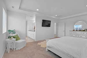 Carpeted bedroom featuring a tray ceiling and ensuite bathroom