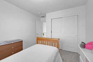 Bedroom with light colored carpet and a closet