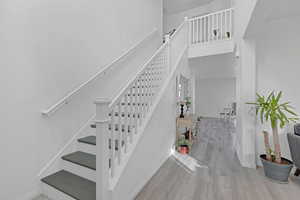 Stairs featuring hardwood / wood-style flooring and a towering ceiling