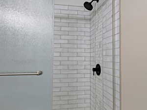 Bathroom with a textured ceiling, toilet, and tiled shower