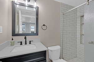 Bathroom featuring vanity, toilet, and a tile shower