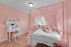 Bedroom with lofted ceiling and hardwood / wood-style flooring