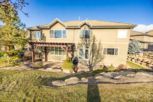 Rear view of house featuring a yard and a pergola