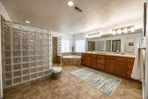 Master bath featuring vanity,  jetted tub, glass tiled shower