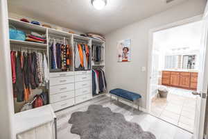 Spacious master closet with light hardwood / wood-style flooring