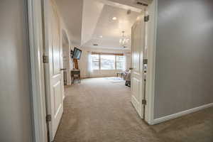 Extra wide hallway featuring raised ceiling with french style doors leading to master suite