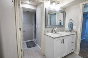 Basement bath connected to bedroom and featuring a shower with door and vanity