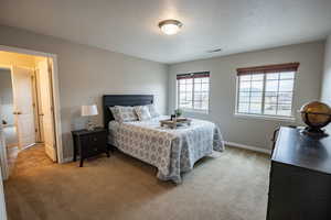 Upstairs bedroom featuring light colored carpet leading into Jack and Jill bathroom