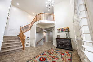 Entryway featuring tile patterned flooring, a towering ceiling, and a notable chandelier