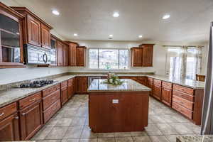 Kitchen featuring light tile patterned floors, a kitchen island, kitchen peninsula, and appliances with stainless steel finishes