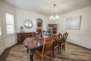 Formal dining room off kitchen featuring wood-type flooring and a chandelier