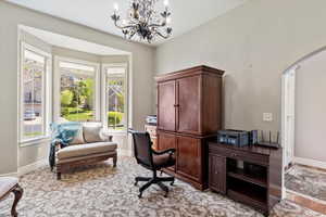 Office with baseboards, arched walkways, and a notable chandelier