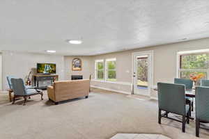 Carpeted living room featuring a fireplace, a textured ceiling, and baseboards