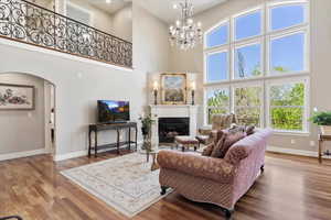 Living room featuring a glass covered fireplace, wood finished floors, a high ceiling, and baseboards