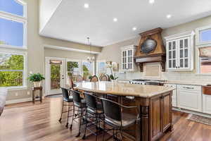 Kitchen with a kitchen bar, a wealth of natural light, a center island, and custom range hood