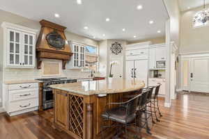 Kitchen with dark wood finished floors, light stone countertops, a kitchen island, and built in appliances
