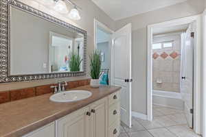 Bathroom featuring shower / bath combo, baseboards, tile patterned flooring, and vanity