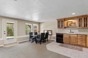 Kitchen featuring glass insert cabinets, black dishwasher, a textured ceiling, and a sink