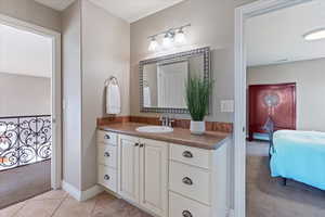 Ensuite bathroom featuring baseboards, tile patterned flooring, vanity, and ensuite bathroom