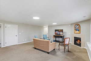 Carpeted living area with a fireplace, visible vents, and baseboards