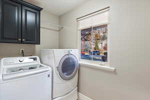 Clothes washing area with washing machine and dryer, baseboards, and cabinet space