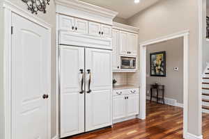 Kitchen featuring tasteful backsplash, wood finished floors, light countertops, stainless steel microwave, and baseboards