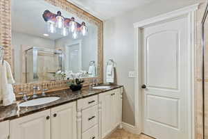 Bathroom with double vanity, tile patterned flooring, a stall shower, and a sink