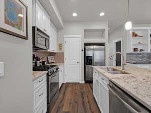 Kitchen with white cabinetry, sink, hanging light fixtures, and appliances with stainless steel finishes