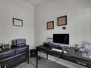 Office area featuring light colored carpet and vaulted ceiling